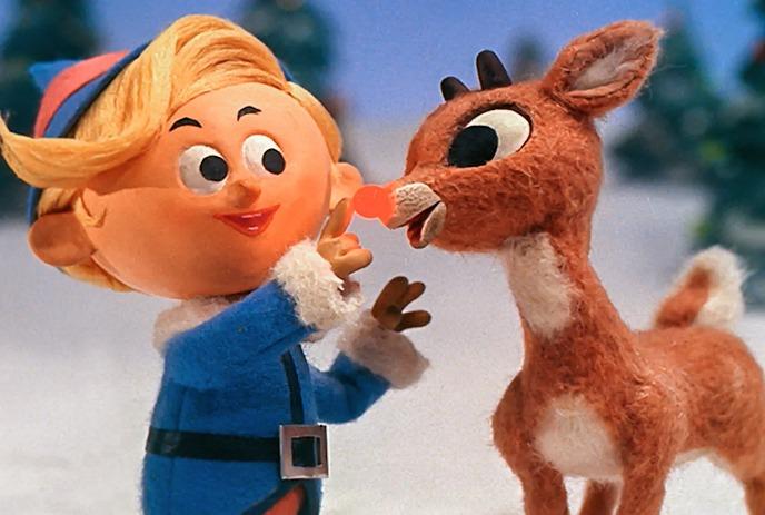 Animated elf and reindeer beside a blank red holiday sign in a snowy forest with decorated trees.