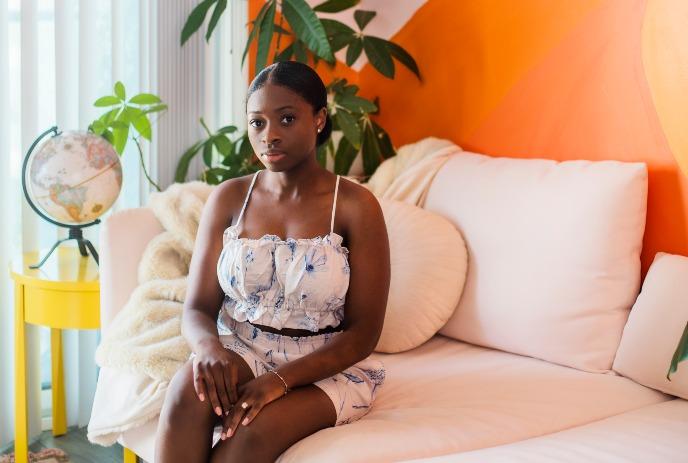 Sammy Jackson sitting on a couch in a colorful room with plants and a globe.