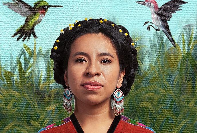 Sara Curruchich with braided hair. flowers earrings and red patterned garment before painted foliage sky and flying birds
