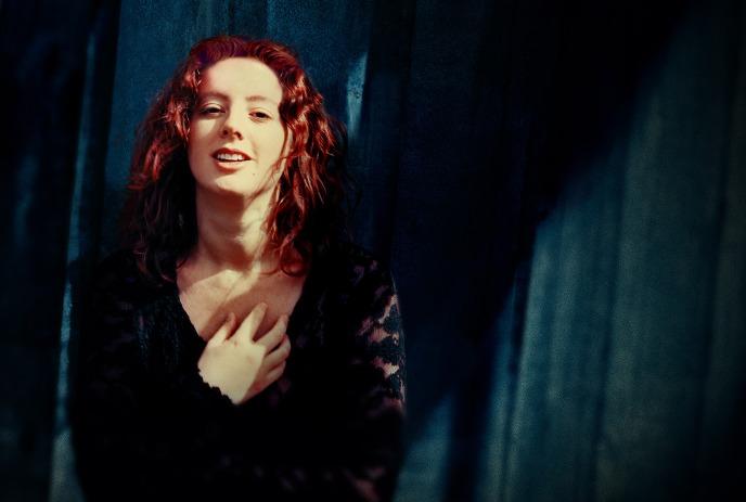 Sarah McLachlan posing for the camera in front of a curtain background.