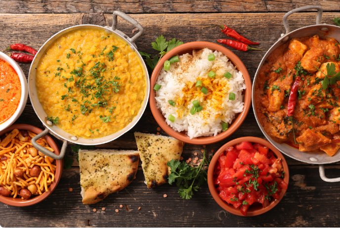 a variety of Indian dishes arranged on a rustic wooden table.