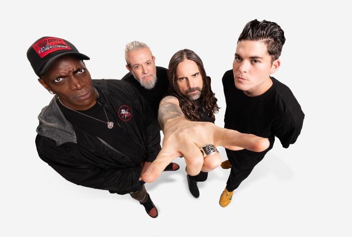 Four band members of Sepultura stand closely together against a white background, looking up with intense expressions.
