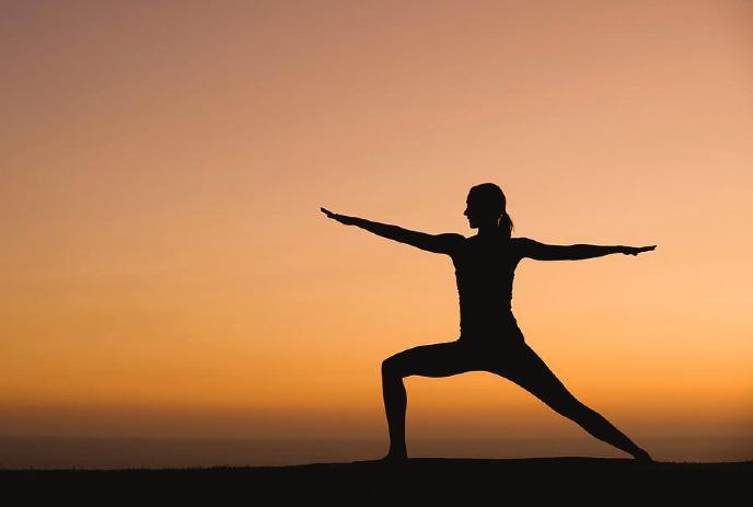 Silhouette of a person practicing yoga during sunset.