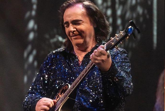 Will Chalmers dressed as Neil Diamond, performing on stage in a sparkly blue suit.