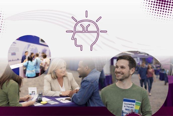 People chat and connect at an indoor event, gathered around tables and booths in a bright, welcoming space.