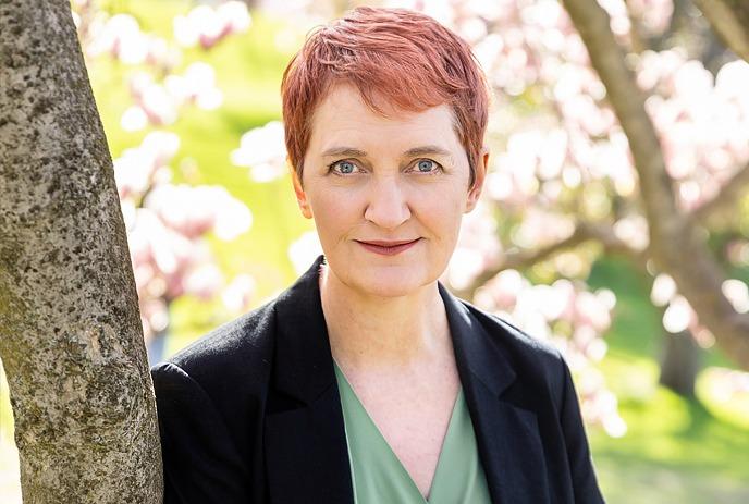 Emma Donoghue stands next to a tree with cherry blossoms in the background.