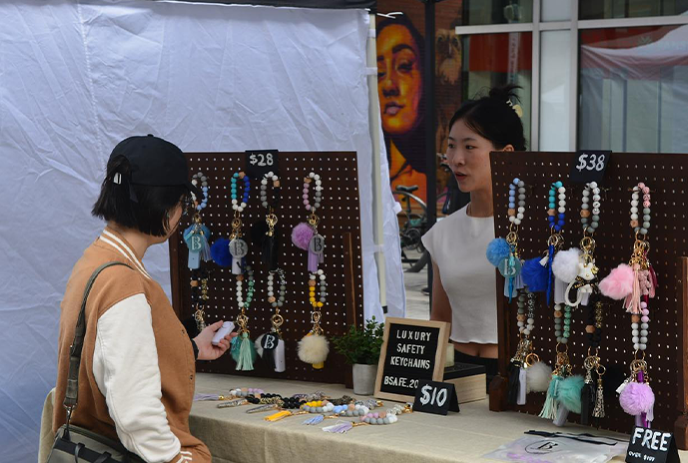 An outdoor market stall displays vibrant handmade jewelry and crafts.
