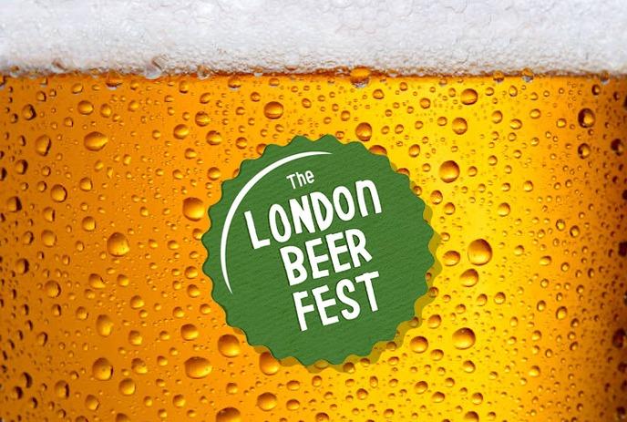 Four raised beer mugs clink together in celebration, against a glowing background of lights indoors.