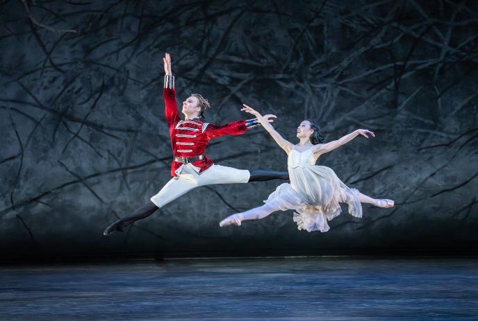 A man and woman performing ballet on stage in costume.