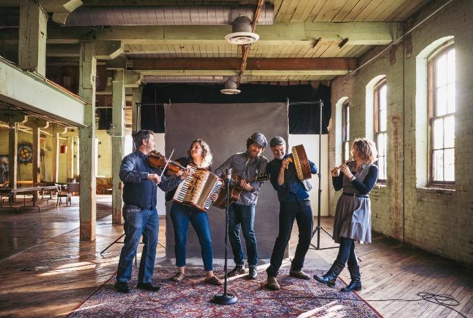 Five band members and their instruments, jamming together inside.