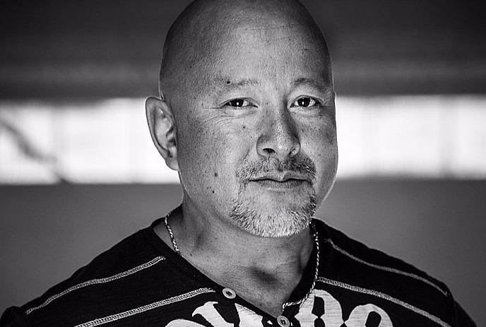 Artistic black-and-white photo of man with necklace, posing for a picture.