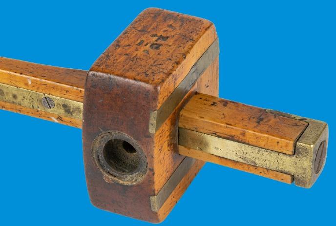An old wooden tool with brass fittings against a blue background.