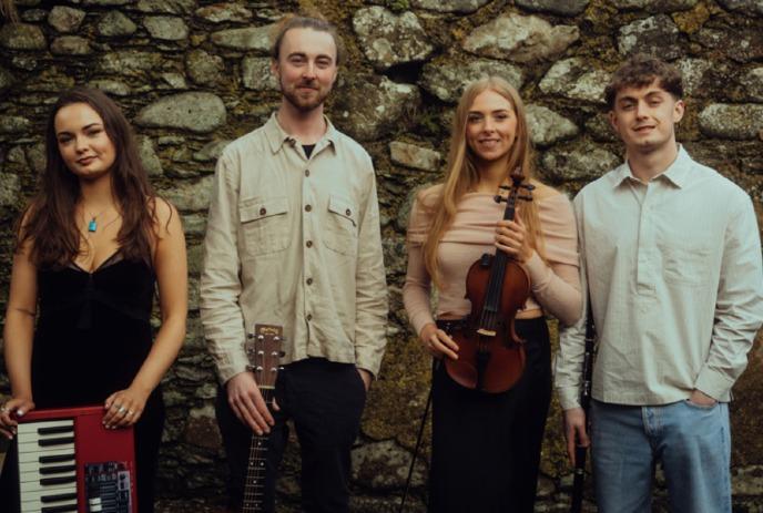 Four artists stand before stone wall holding keyboard guitar violin while fourth stands calmly completing ensemble.