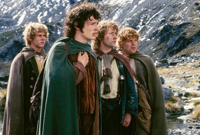 Four figures stand together in rugged mountains gazing outward with shared resolve and quiet focus.