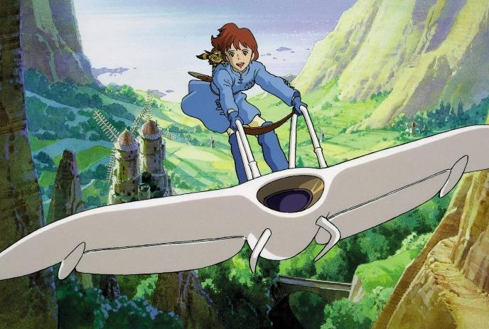 A person with auburn hair, wearing a blue outfit, joyfully glides on a white glider over a lush, green valley.