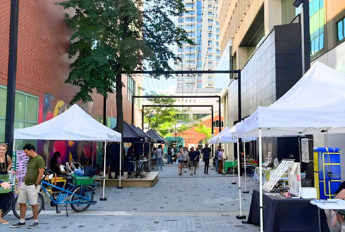 Market lane in London, Ontario, lined with vendor tents and people.