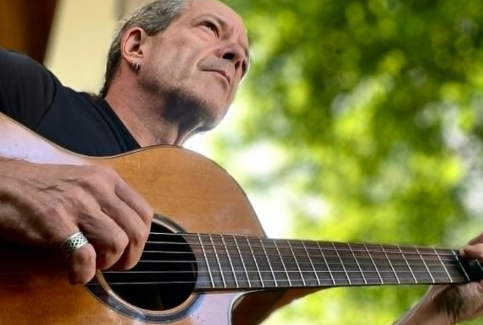 Dave sitting under a tree playing guitar.