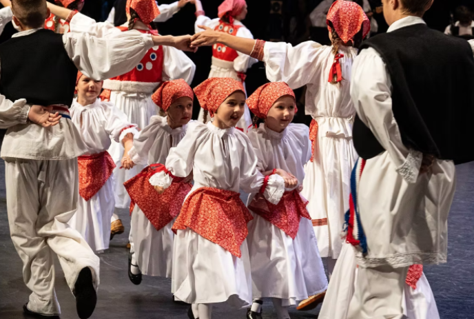 Young people in traditional red and white dress dancing in between older people.