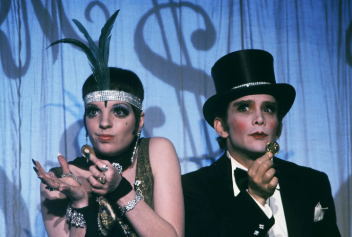 Two people dressed in Cabaret outfits on stage together.