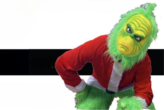 A person in a Grinch costume with a Santa jacket, white fur trim, standing playfully in a festive setting.