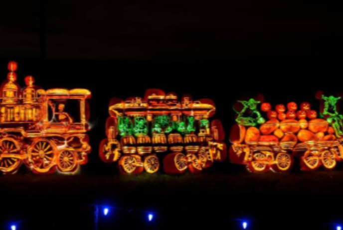 Train at night with orange lights and pumpkins on it.