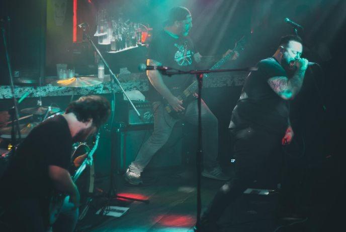 Band performing live with vivid lights, guitars, drums, and a singer passionately singing on the vibrant stage.