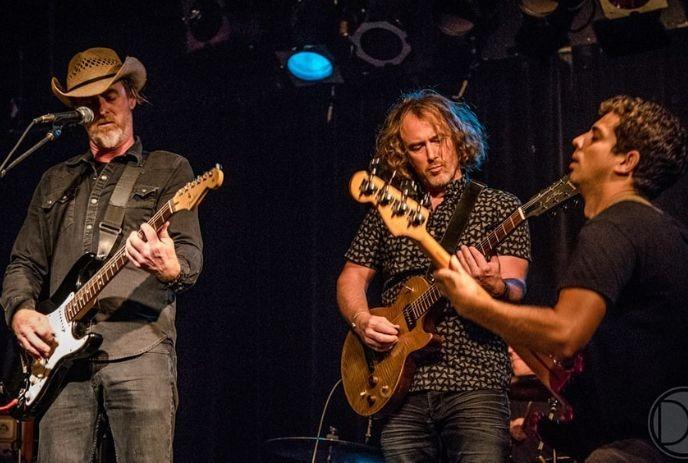 Musicians on stage with guitars, playing under vibrant lights, creating an energetic live performance vibe.