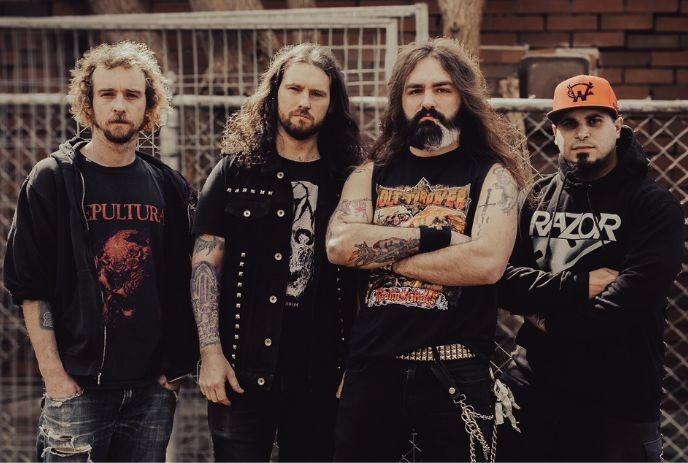 Four band members in black outfits posing for a picture.