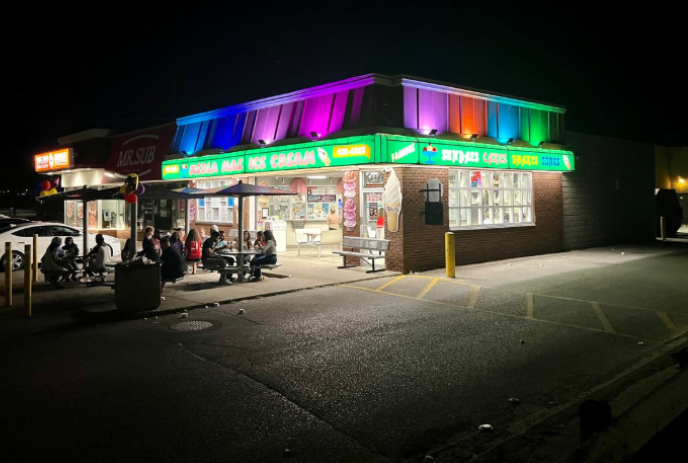 Merla Mae at night with different coloured lights around the outside of the building.