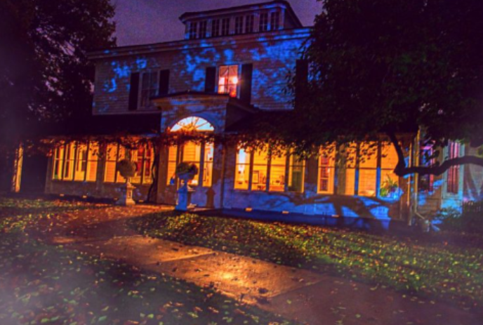 Eldon House in the fall at night with lights glowing from the windows.