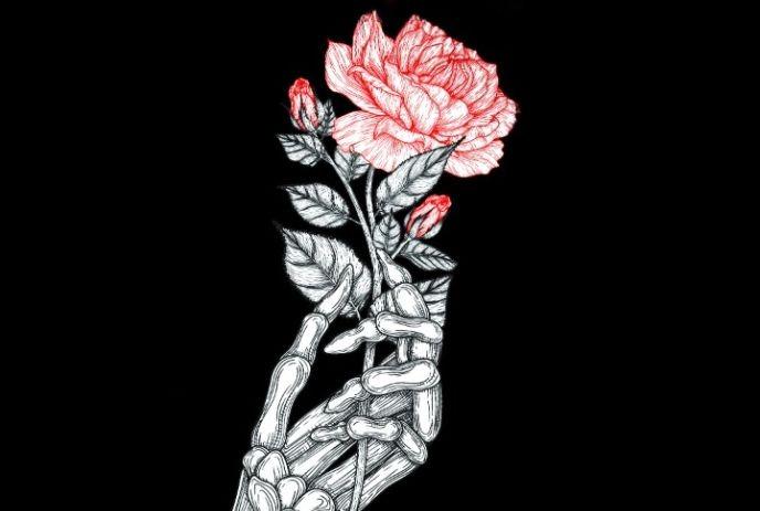 Skeletal hand holds blooming rose, red petals with black and white leaf's under a black background.
