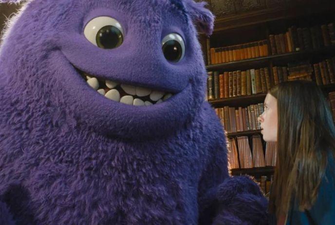 Young person smiles up at a large, furry purple creature in a library; whimsical, friendly, and imaginative moment.