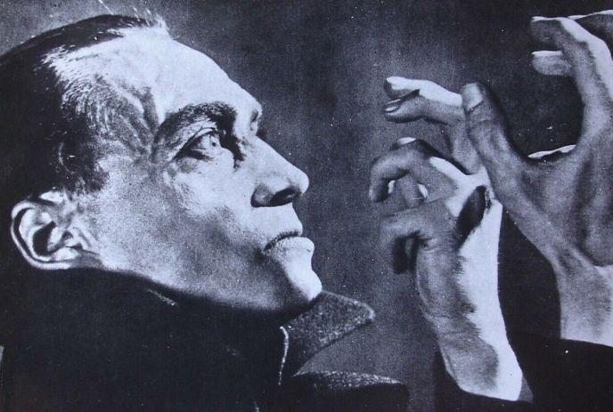 Black-and-white portrait of person with raised hands, dramatic shadows, theatrical expression.