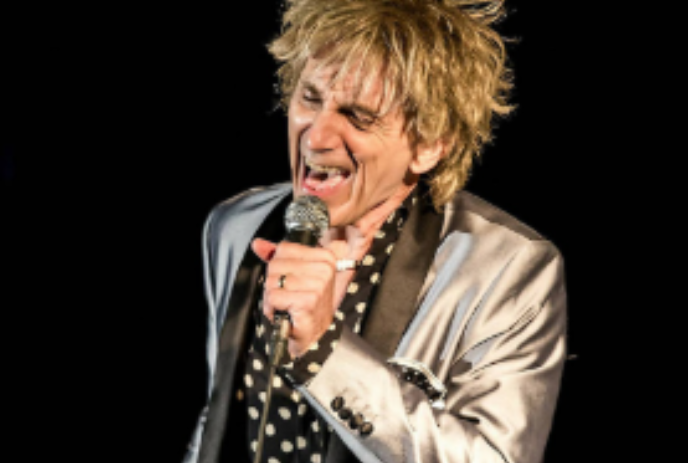 Doug Varty dressed as Rod Stewart performing on stage.