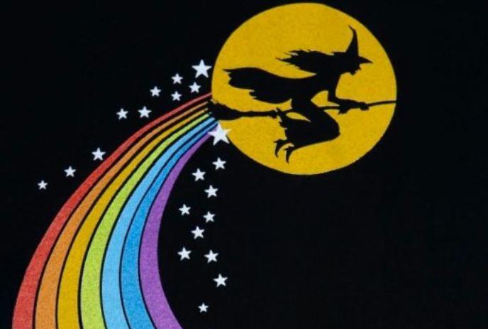 Witch silhouette flies past yellow moon, trailing rainbow and stars on black sky.