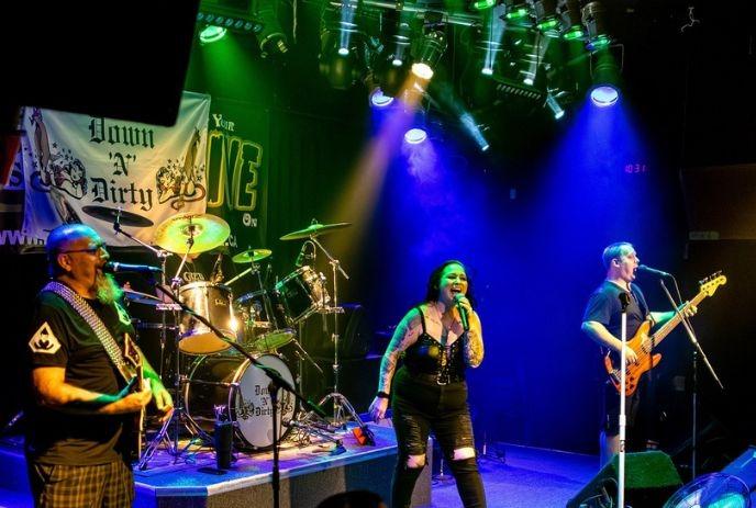 Down 'N' Dirty performs on stage with vibrant green-blue lights; vocalist leads guitar, bass, drums.