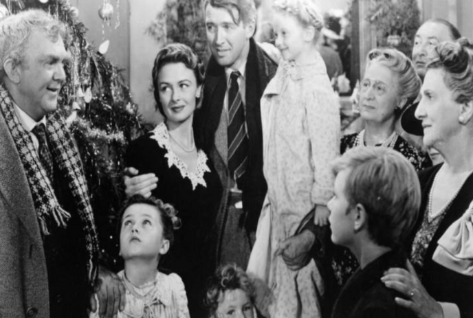 Black and white image of a group of people looking expectantly at one person.