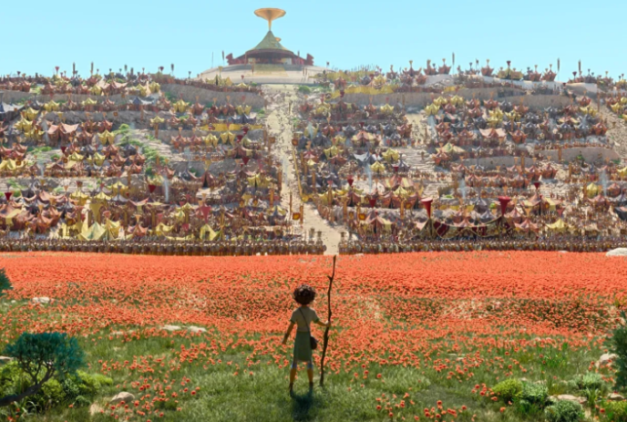 A young man holding a stick stands in front of a large group of tents on a hill.