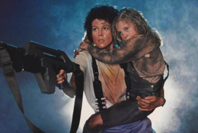 Person holding a young child while pointing a machine gun at something offscreen.