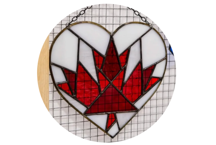 Heart shaped stained glass ornament with a maple leaf in the centre.