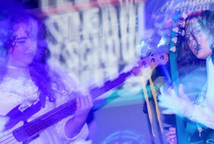 Two musicians playing guitars under purple-blue stage lights, motion blur, live performance energy