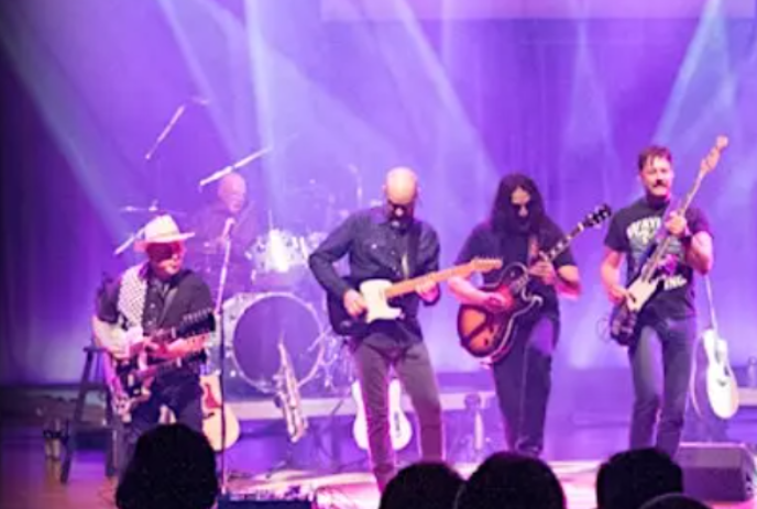 Band members on stage playing with purple lights in the background.