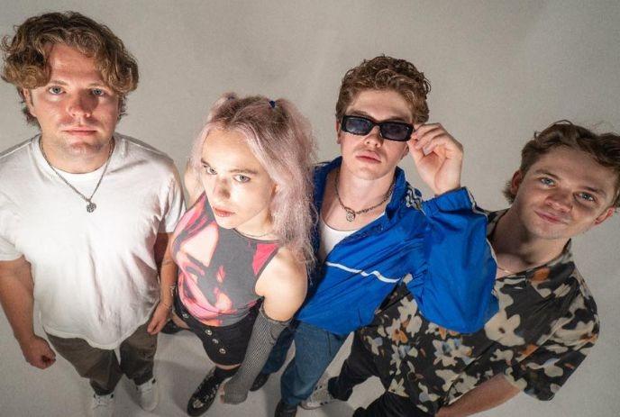 Four artists standing close together looking upward under the white background.