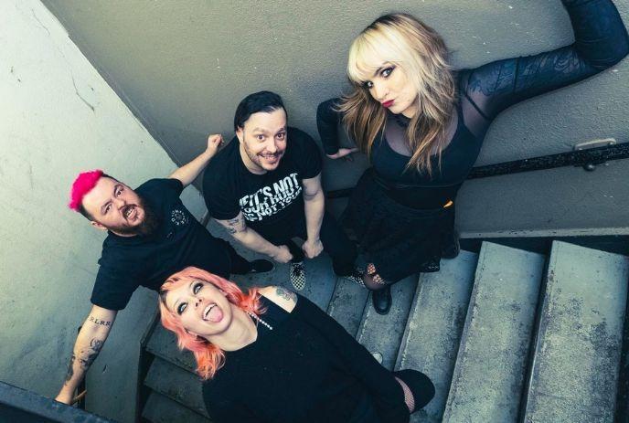 Four artists on a stairwell looking up, posing with an energetic vibe.