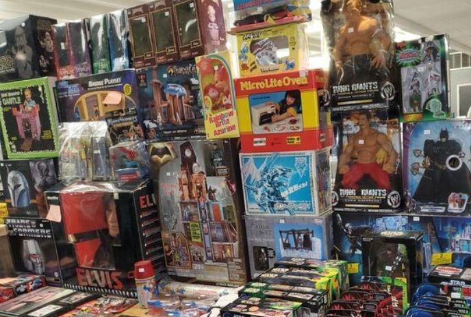 A crowded booth shows shelves of colorful toys figures and retro items arranged for shoppers.