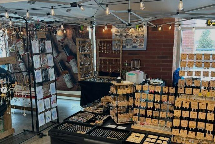 Handmade jewelry stall glowing with warm lights and rows of earrings bracelets and charms.