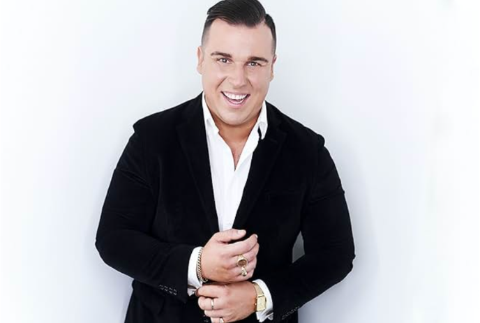 Eric Johnston wearing a black sport jacket holding his sleeve.