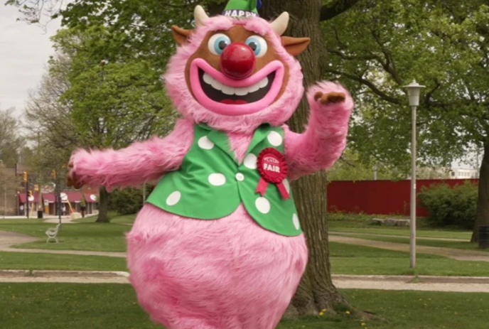 Happy, the pink Western Fair mascot walks inside the fairgrounds.
