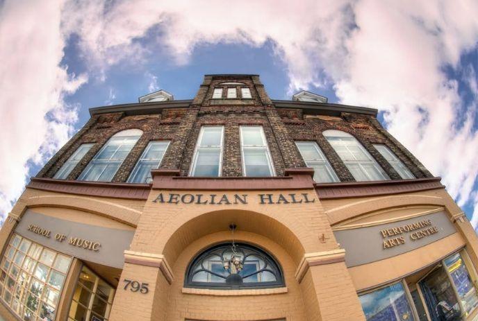 Front view of Aeolian Hall with arched windows, brick detailing, and a bright sky above.