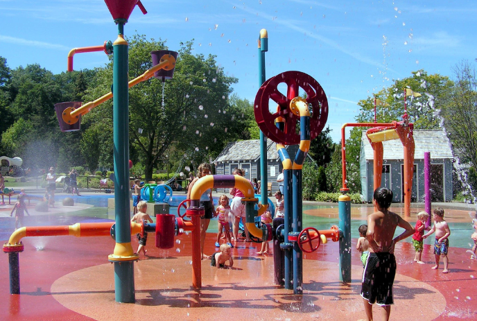 Children happily playing in the splash pad on a summer day.